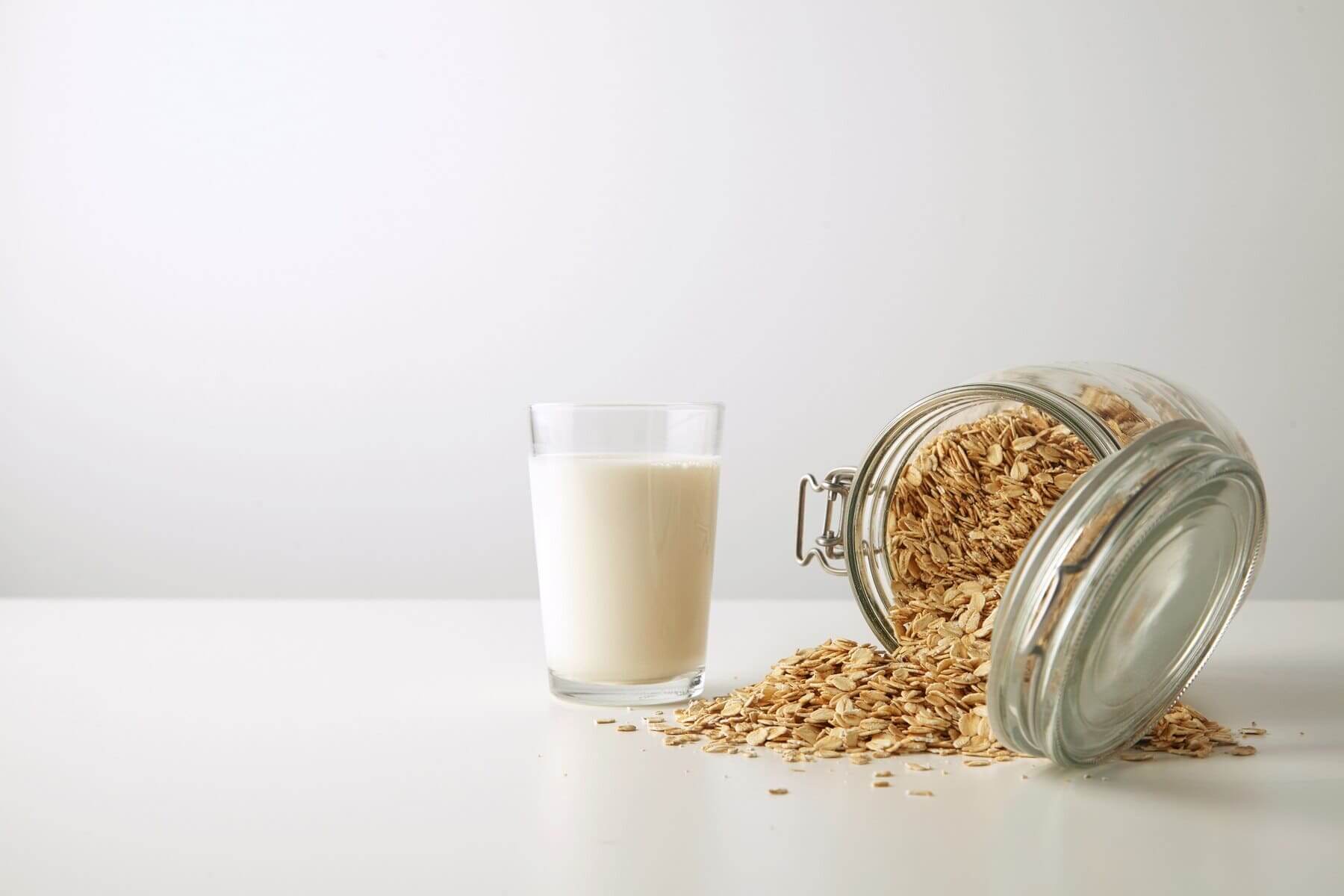 Low calories oat milk on a table next to a jar of oats