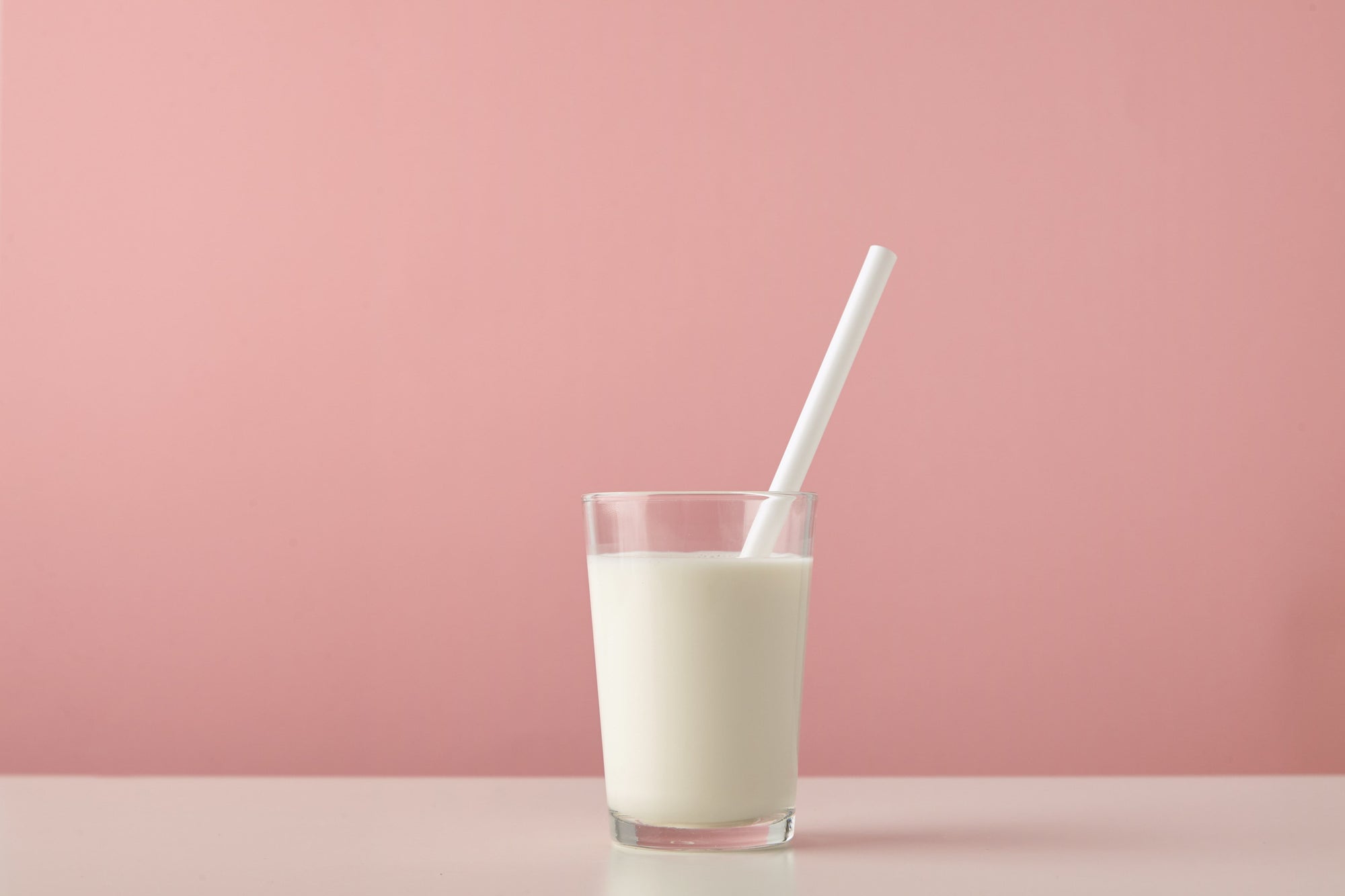 Does oat milk have calcium represented by milk glass on pink background
