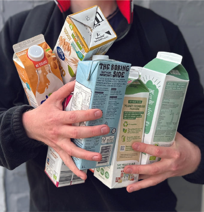 Person holding 8 oat milk cartons in their hand