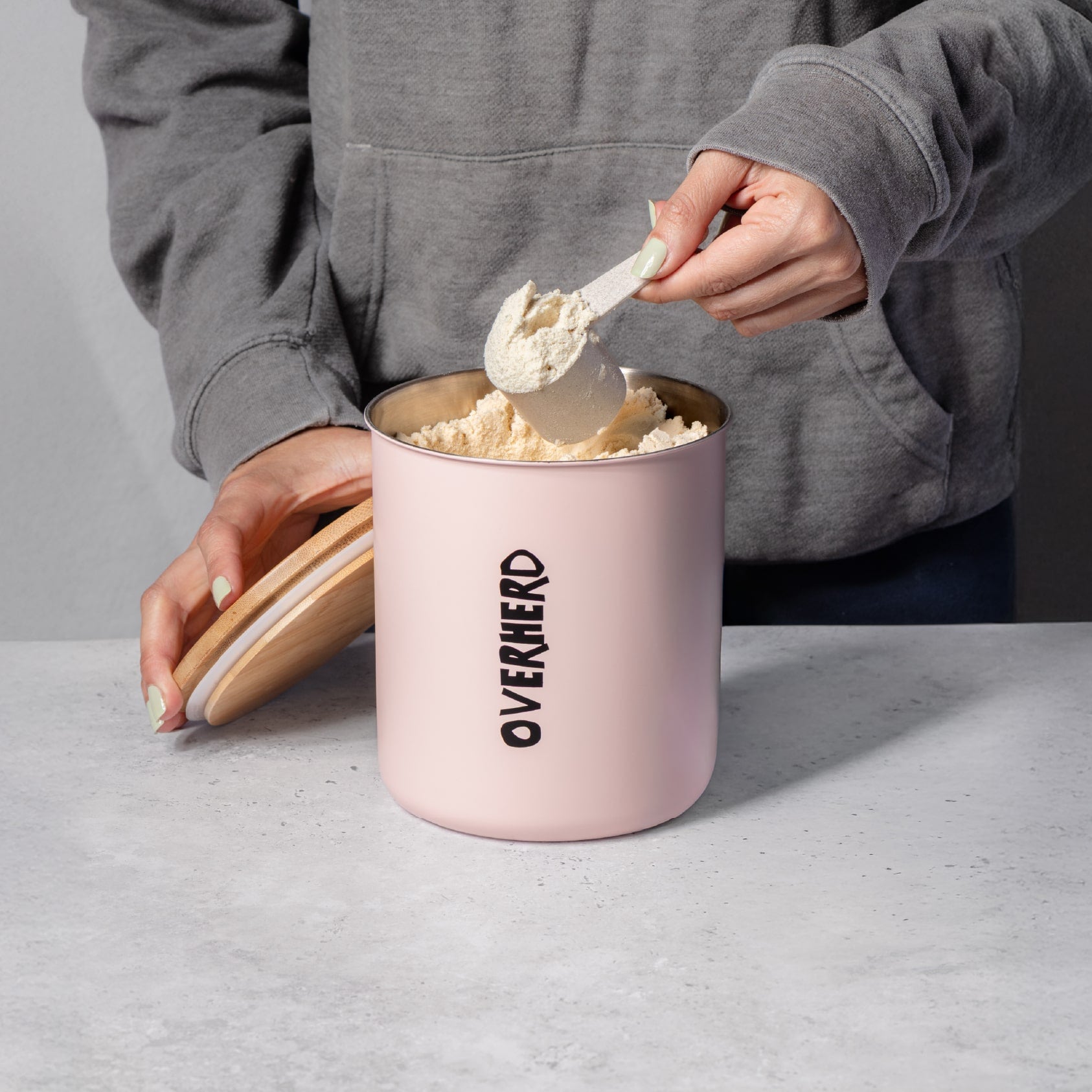 Scooping oat milk powder out of the Overherd storage tin