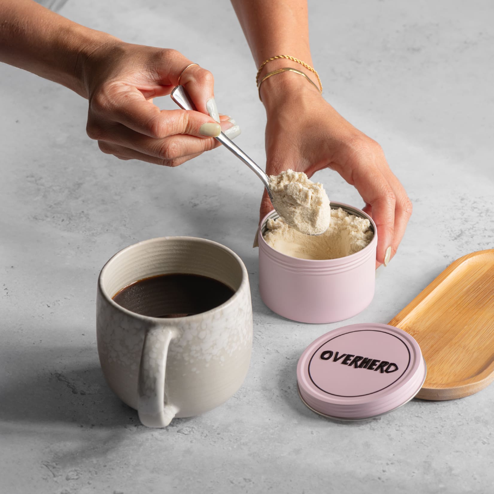 Scooping oat milk powder out of travel tin and into a cup of coffee