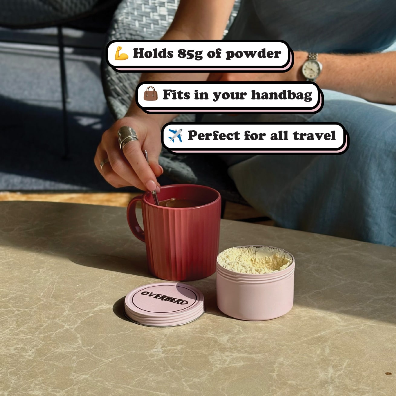 Girl stirring oat milk powder from a travel tin into a coffee in dark red mug