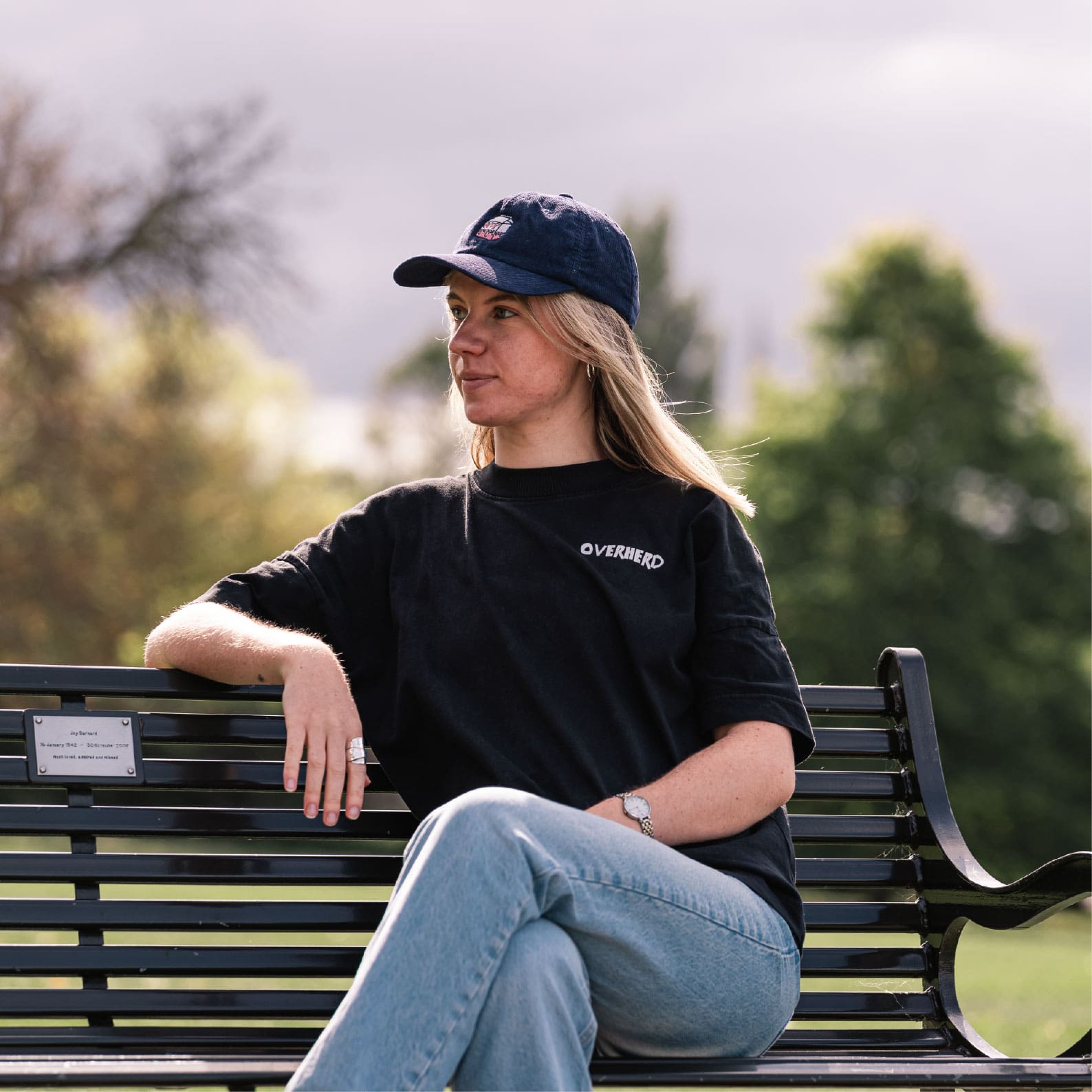 Girl sitting on bench wearing black oat milk t shirt