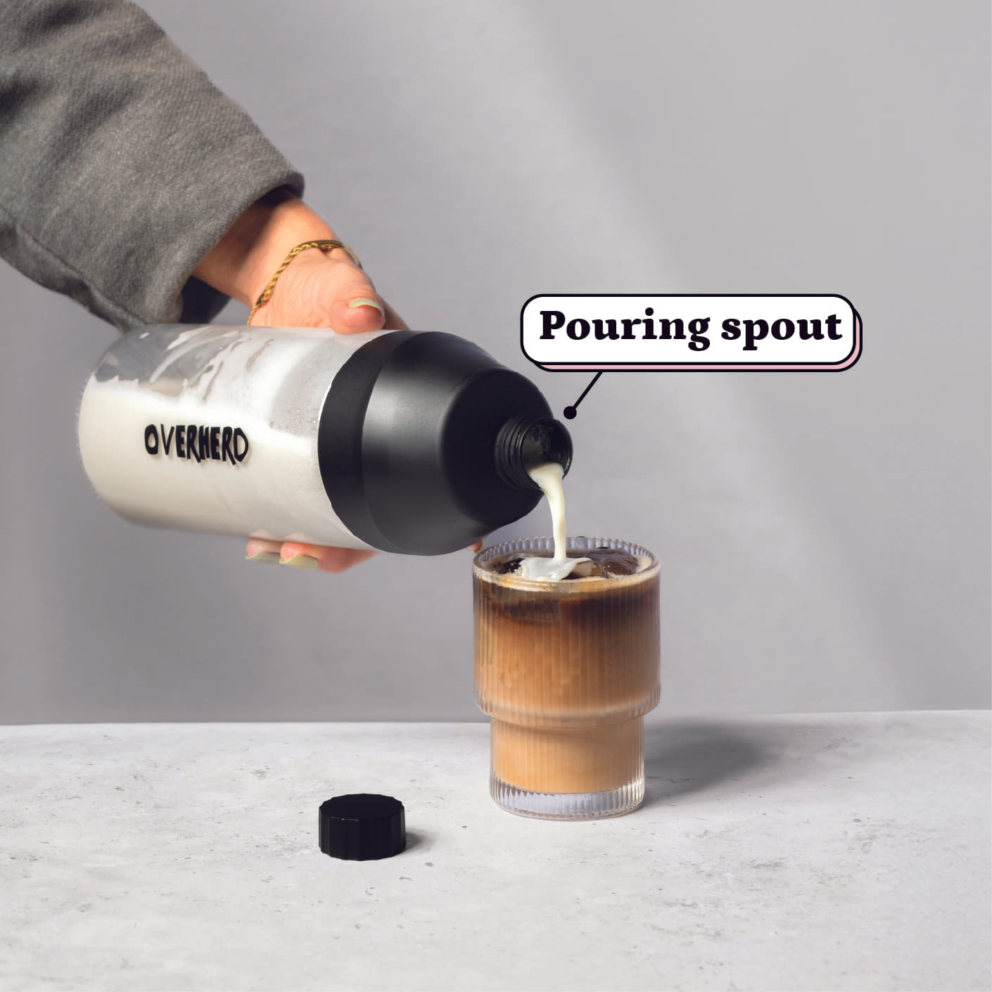 Pouring oat milk from glass bottle into coffee