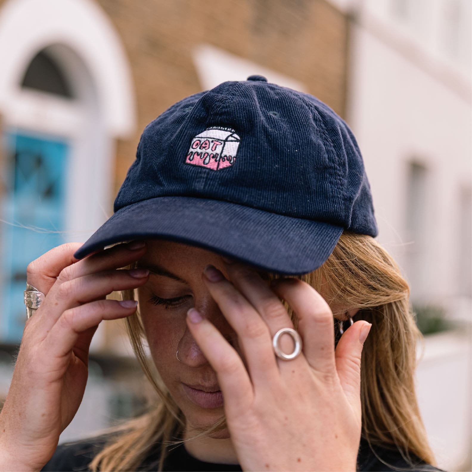 Girl wearing navy corduroy oat milk cap in front of house