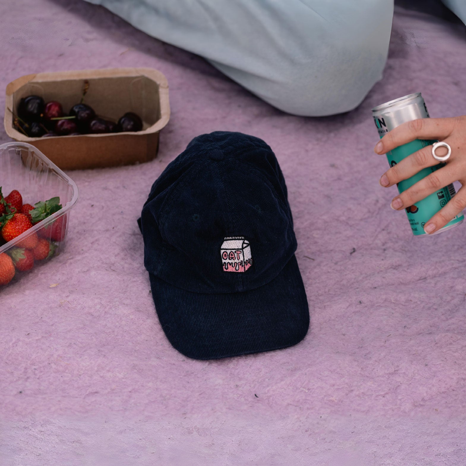 Navy corduroy oat milk cap on a purple picnic blanket