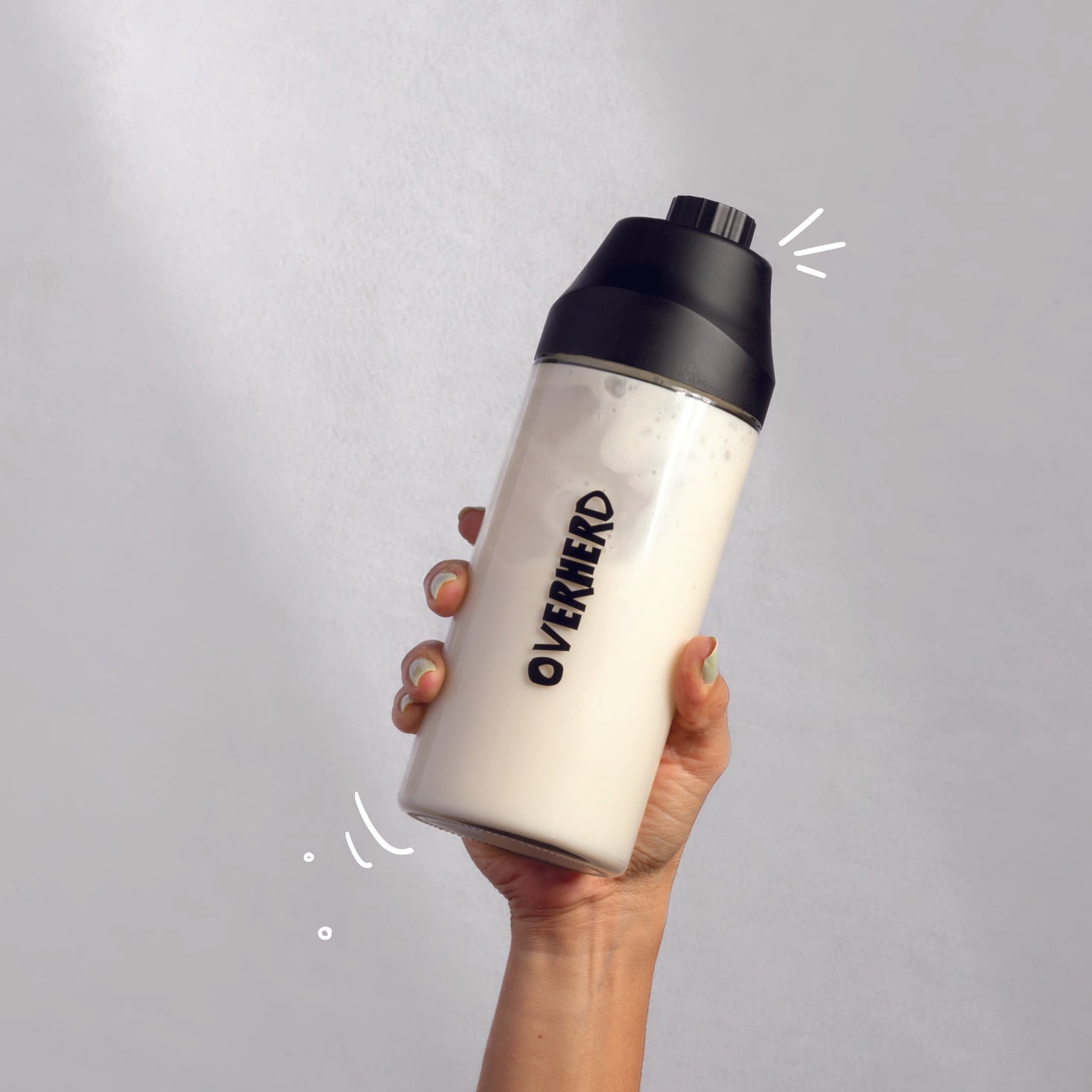Hand holding up a bottle of Overherd oat milk