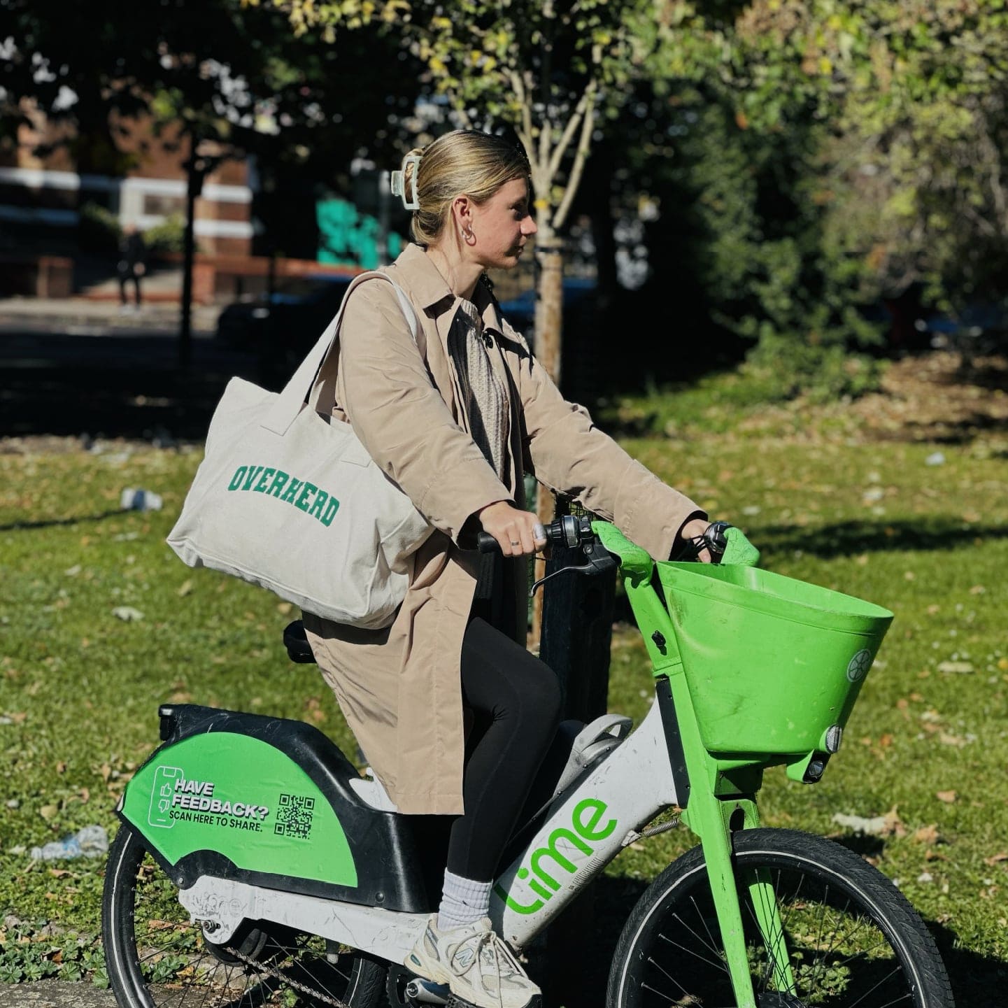 Girl riding Lime bike with Overherd tote bag over shoulder